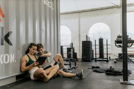 Gym paperwork organization: Couple using tablet to manage fitness plans and workout schedules in a gym setting.
