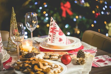 Festive holiday table setting with Christmas tree, cookies, wine glasses, and candle, promoting healthy holiday season.