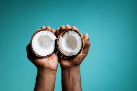 Hydration tips: Hands holding halved coconut. Coconut water for staying hydrated, a healthy and natural source of electrolytes.