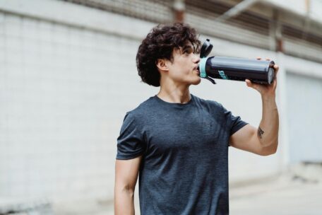 Hydrated fitness: Man drinking water from bottle. Stay hydrated with our top tips for healthy living and exercise routine.