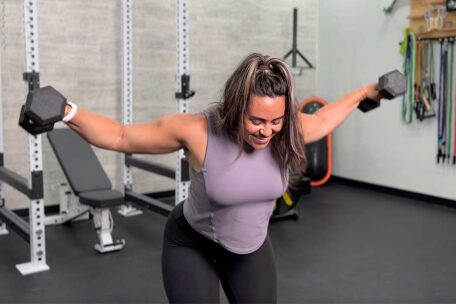 Woman doing reverse fly exercise with dumbbells for posture improvement in a gym setting. Strength training.