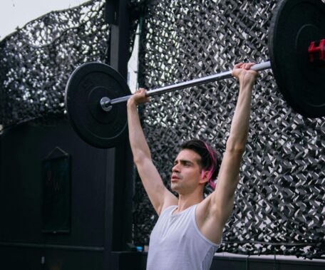Overhead press: Man lifting barbell in gym. Compound exercise for strength training and muscle building.