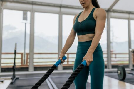 Woman doing battle rope exercises in gym. Full body workout with fitness rope. Strength and cardio training.
