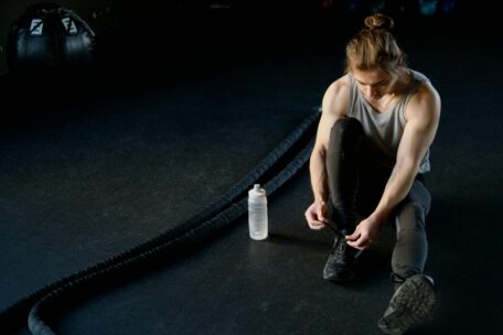 Man tying shoe next to battle ropes in gym. Focus before battle rope exercises and workouts. Strength training and fitness.