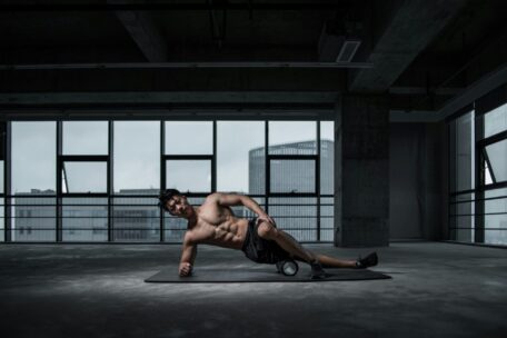 Foam roller exercise: Man using foam roller for muscle recovery in a gym. Fitness and wellness concept.