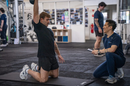 Personal trainer coaching man lifting kettlebell in gym. Fitness instructor guides client. Successful personal trainer qualities.