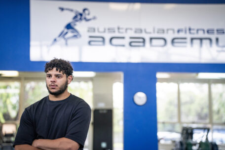 Successful personal trainer with arms crossed at Australian Fitness Academy gym, a quality for a great trainer.