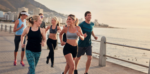 Group of athletes running along a seaside promenade